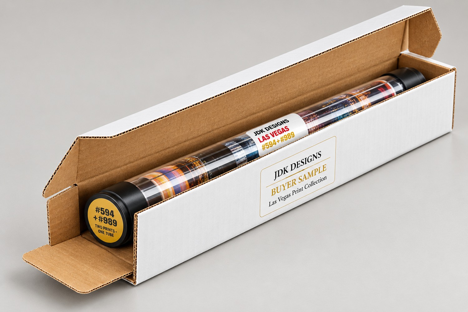 Illustrative JDK Designs buyer sample: a clear print tube with black end caps inside an open white shipping carton